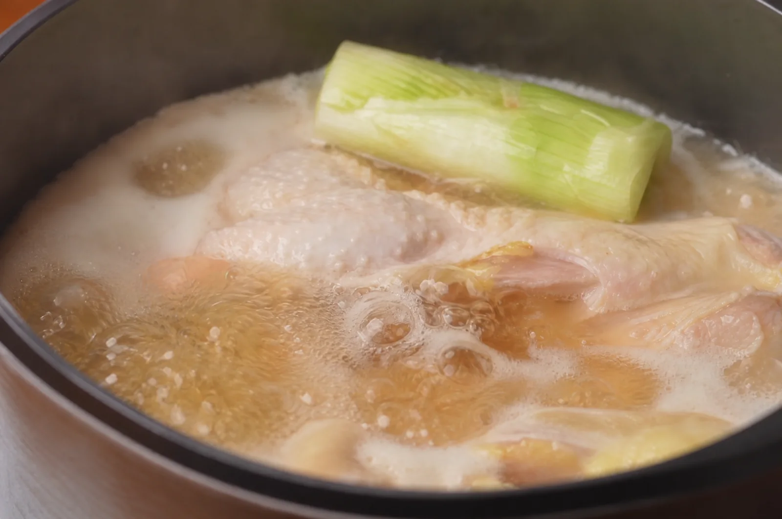 Chicken gently simmering with scallions in a cooking pot